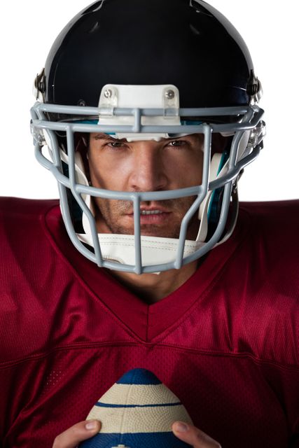 Portrait of determined American football player wearing helmet holding ball against white background