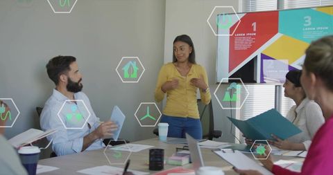 Female presenter leading team meeting with colorful infographic slide in modern boardroom