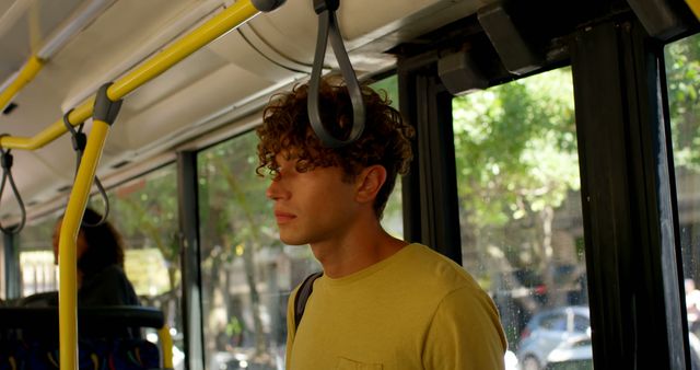 Biracial man with curly hair standing in city bus. Transport, city living and lifestyle, unaltered.
