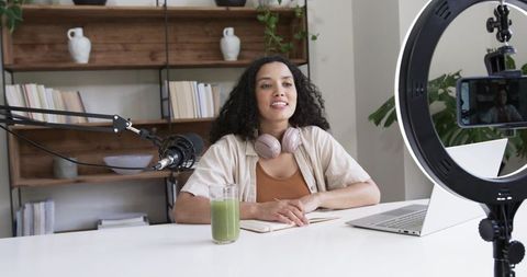Content creator hosting podcast in home studio with ring light, microphone and laptop