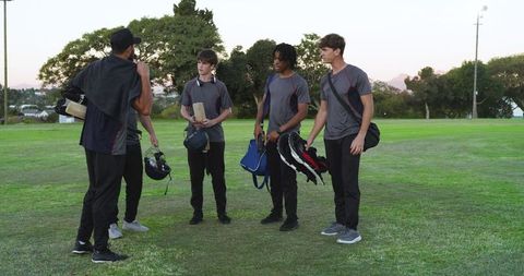 Coach giving guidance to diverse young cricket players walking off field after training