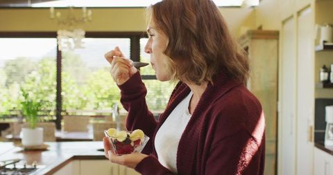 Pregnant woman enjoying ice cream in bright kitchen