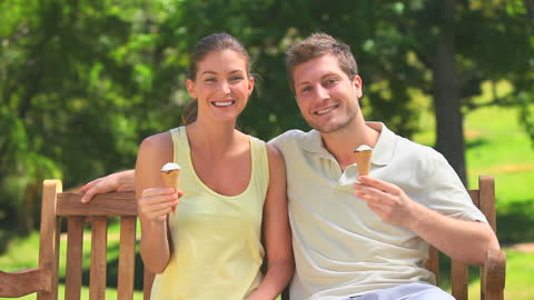 Smiling Couple Enjoying Ice Cream in Sunny Park