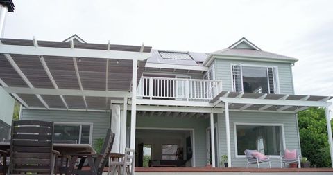 Coastal two-story home with pergola deck, upper balcony, glass doors and solar panels