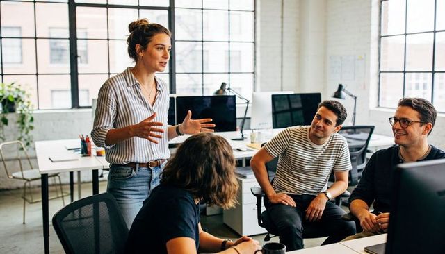 Female team leader presenting ideas to colleagues in bright open office during meeting