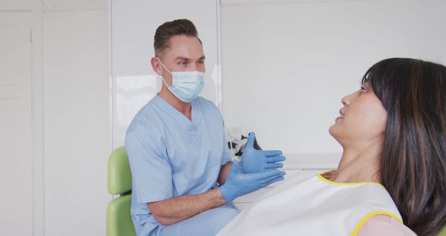 Caucasian male dentist wearing face mask prepares a smiling female patient at a modern dental clinic. This image is ideal for illustrating themes of healthcare, dental care, safety procedures during the Covid-19 pandemic, and the importance of hygiene and modern treatments in dentistry clinics. It can be used in dental care advertisements, Covid-19 safety guideline brochures, healthcare websites, and business promotions for dental practices.