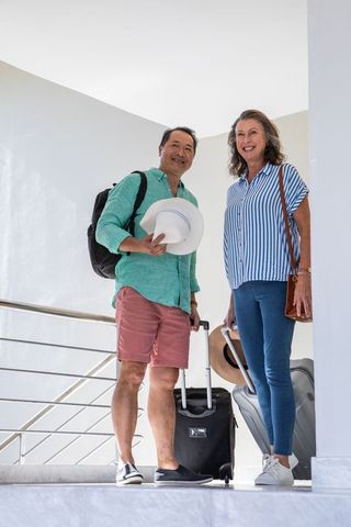 Smiling couple with luggage at hotel stairs