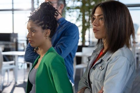 Two diverse coworkers listening intently in sunlit modern office coworking space with greenery
