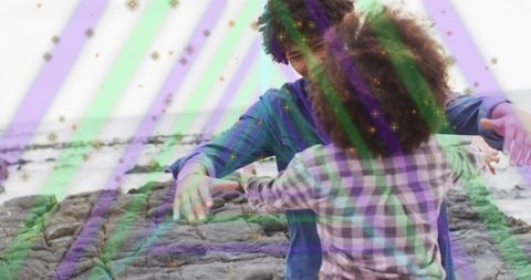Couple embracing on rocky shore with creative light overlay