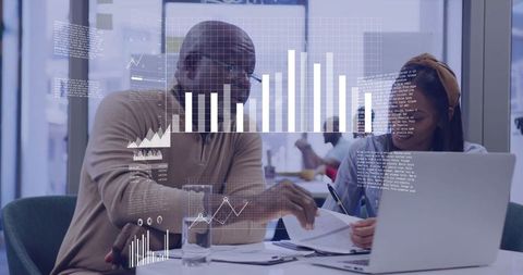 Senior mentor and young mentee collaborating over laptop in modern office