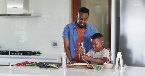 Smiling Father and Son Preparing Homemade Pizza Together