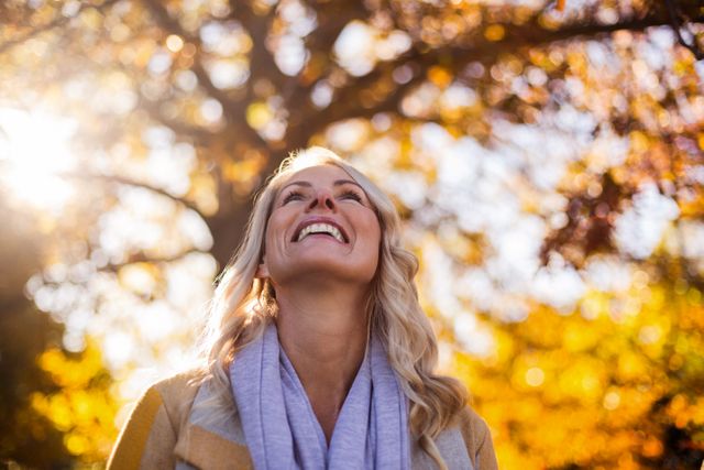Smiling Woman Enjoying Autumn Sunlight in Park - Download Free Stock Photos Pikwizard.com