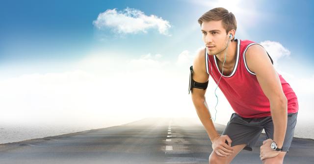 Young male runner pausing on a road under a sunny sky, wearing headphones and sportswear. Ideal for fitness, running, exercise, health, determination, technology in sports, outdoor activities and wellness promotions.