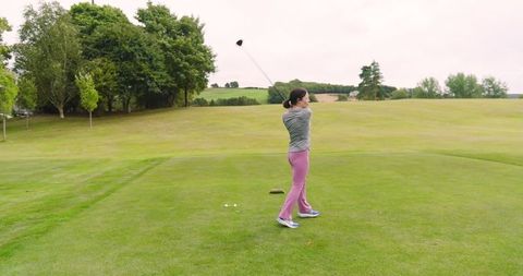 Woman perfecting golf swing on lush green course