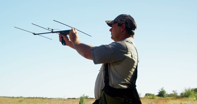 Man operating bird tracking device with antennas in an open field. Useful for topics related to wildlife research, conservation efforts, outdoor activities, environmental sciences, and field studies.