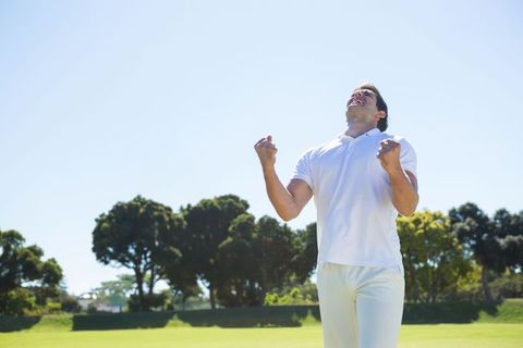 Joyful male athlete celebrating victory on green field
