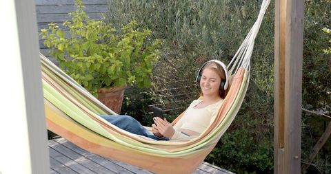Woman Relaxing in Outdoor Hammock with Headphones and Smartphone