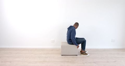 Man Stretching beside Ottoman in Minimalist Living Room