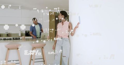 Couple collaborating remotely in modern kitchen using laptop and smartphone with AR overlay