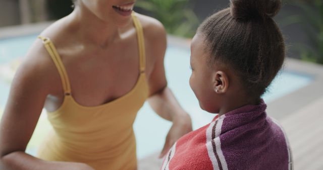 Mother wrapping her child in a towel beside a swimming pool. Represents family bonding moments, care, and summertime activities. Ideal for use in family-centered advertisements, lifestyle blogs, and parenting magazines.