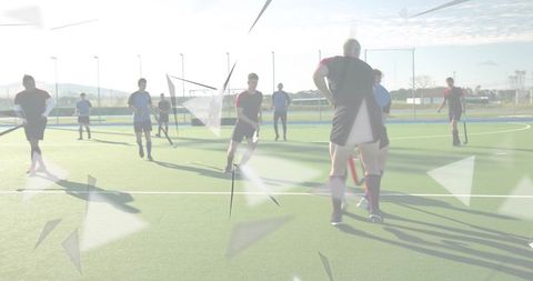 Field hockey players standing and watching play on sunlit turf with geometric overlays