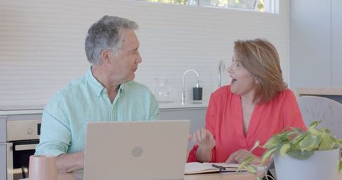 Senior Couple Joyfully Discussing Ideas at Home Kitchen Table