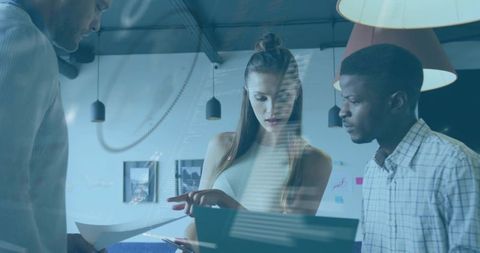 Young intern leading team pointing at laptop during collaborative office brainstorming
