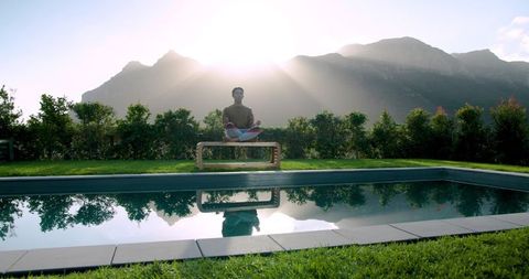 Meditating Near Pool with Mountain Sunrise