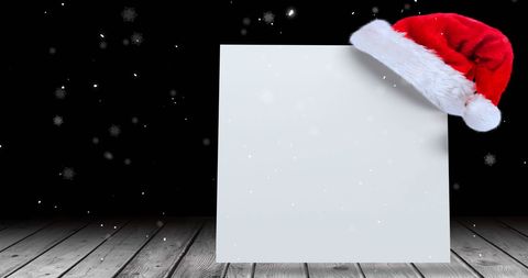 Snow Falling over Blank Card with Santa Hat on Rustic Wooden Deck