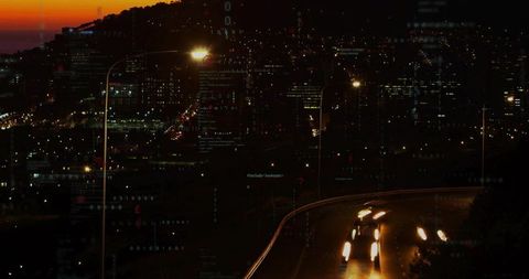 Curving coastal highway glowing with headlight trails at dusk