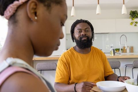 African american father and teenage daughter sharing quiet mealtime at kitchen island