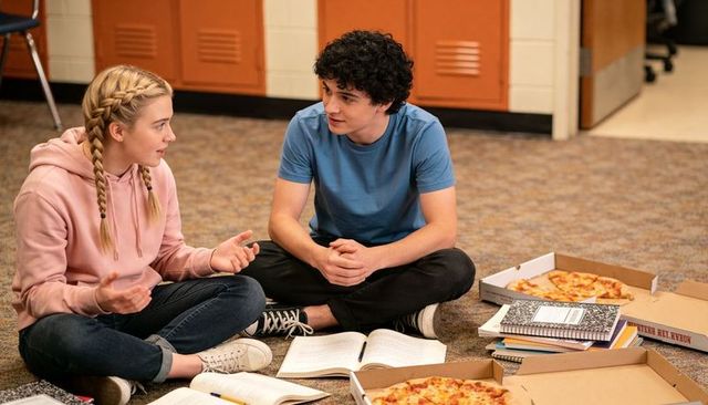 Teen classmates studying and sharing pizza on school floor by lockers friendly study session