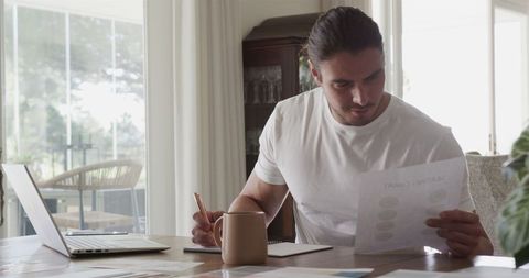 Man focusing on work at home office with coffee and laptop