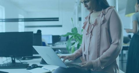 Businesswoman typing on laptop in modern open workspace
