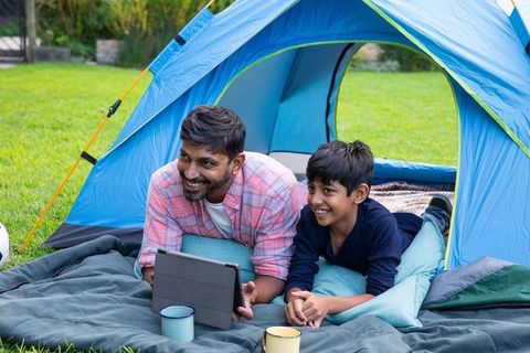 Father and Son Bonding During Camping Trip with Tablet
