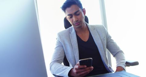 Business Professional Checking Smartphone in Bright Office