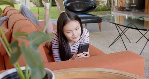 Young woman lounging with smartphone in cozy living space