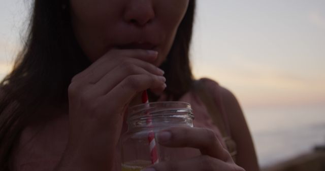 Woman Drinking Beverage with Red and White Straw at Beach Sunset - Download Free Stock Images Pikwizard.com