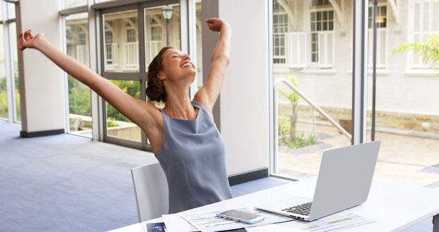 A young Caucasian woman celebrates a moment of success or relief at her workplace, with copy space - Download Free Stock Photos Pikwizard.com