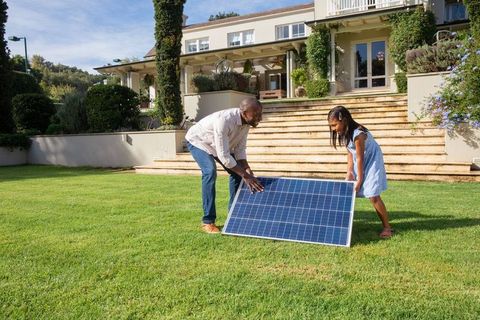 Father and Daughter Install Solar Panel on Lawn of Modern Home