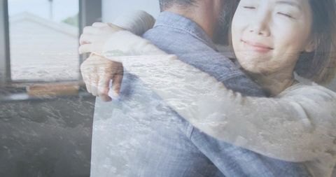 Double exposure couple embracing with ocean waves overlay, intimate home moment