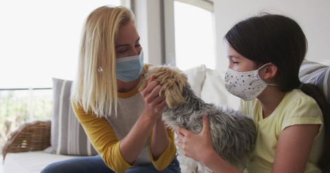 Masked Mother and Daughter Bonding with Dog at Home