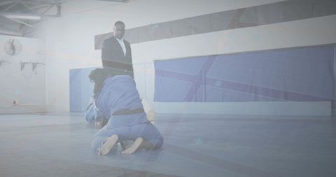 Grappling opponents in blue gis exchanging ground holds during brazilian jiu-jitsu training