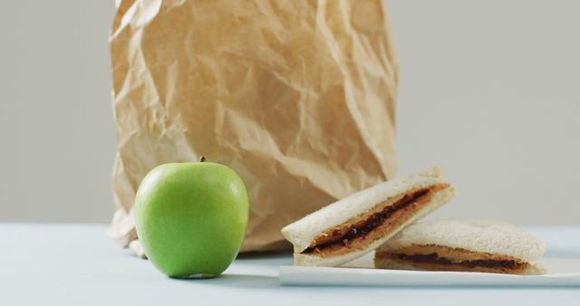 Peanut butter and jelly sandwich with apple and paper bag against white background. food and nutrition concept