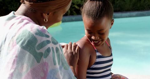 Mother and Daughter Poolside Applying Sunscreen on Sunny Day