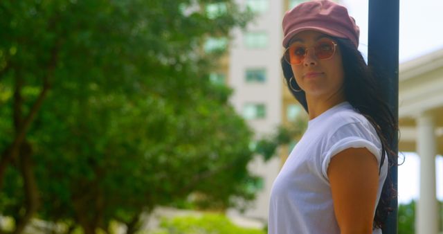 A young Caucasian woman wearing a pink cap and sunglasses stands outdoors, with copy space - Download Free Stock Photos Pikwizard.com