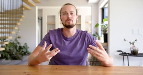 Young man with light brown hair speaking on virtual call at home
