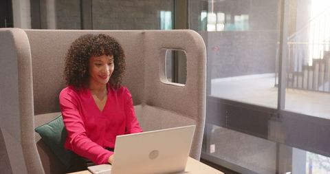 Businesswoman typing on silver laptop in modern workspace