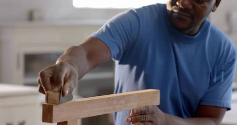 Smoothing hardwood with hand plane by skilled craftsman in home woodshop, close-up