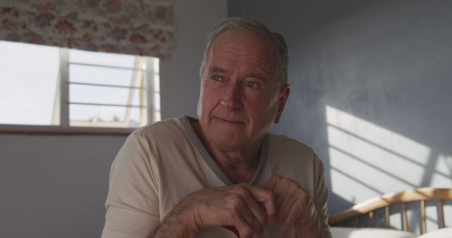 Contemplative Elderly Man Sitting in Sunlit Room - Download Free Stock Images Pikwizard.com